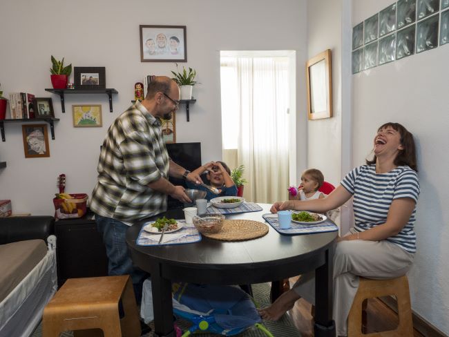 A family meal - parents and two young children sitting around a table in the family home.